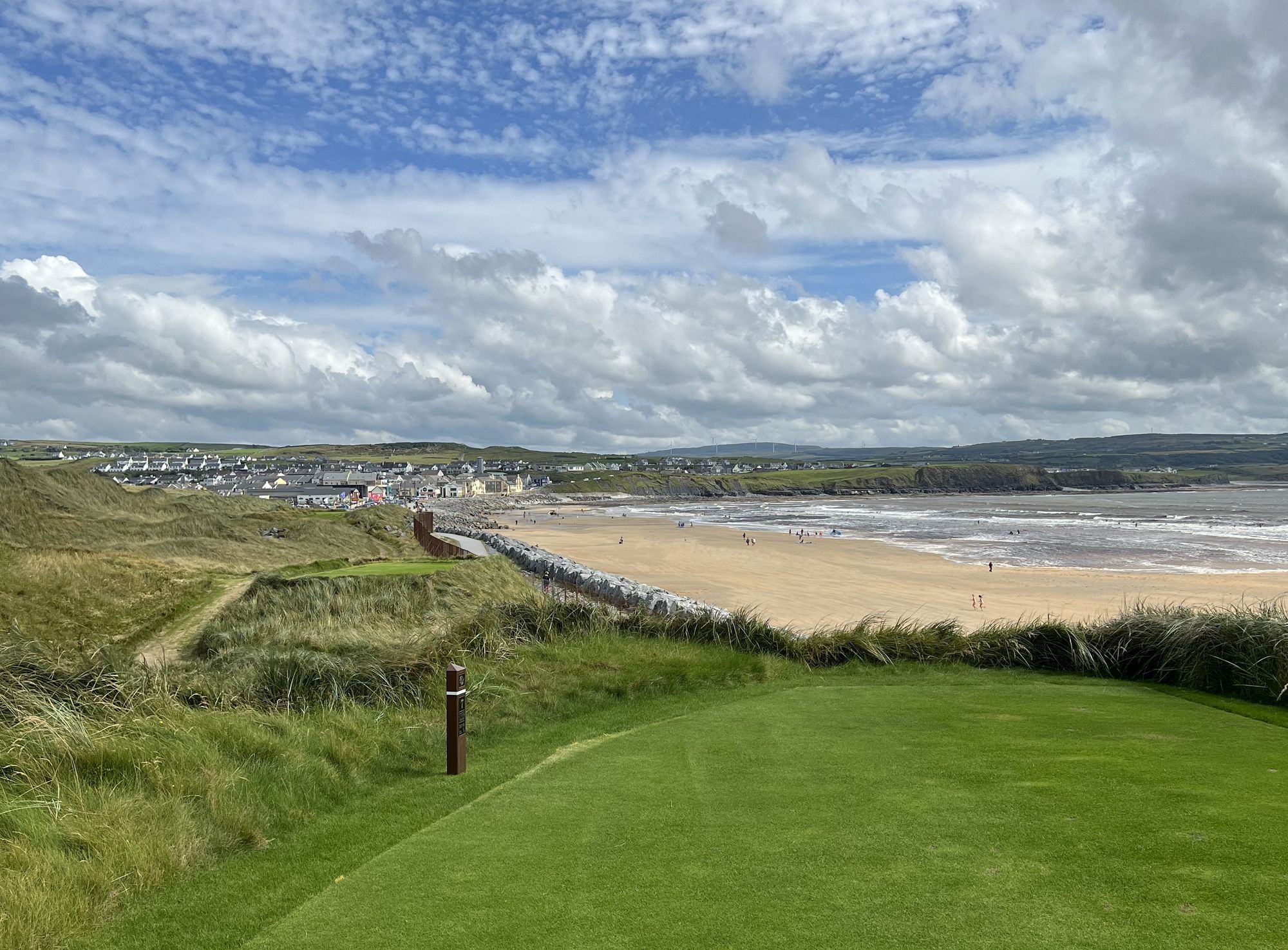 View from an elevated tee at Lahinch Golf Links, looking over the dunes to the beach and village beyond